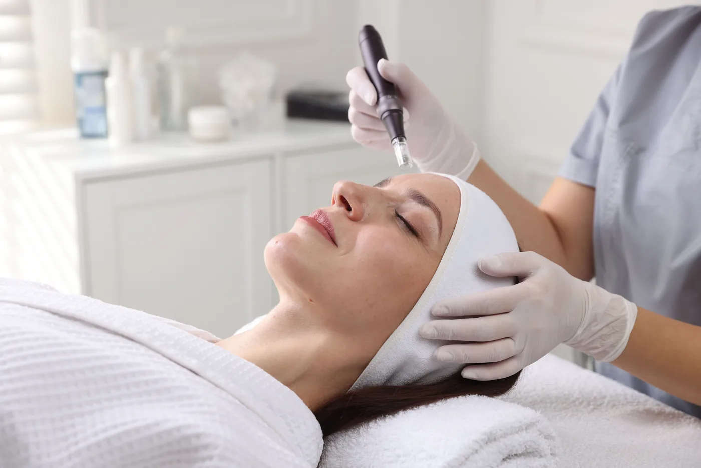 Woman receiving a microneedling facial in a bright treatment room