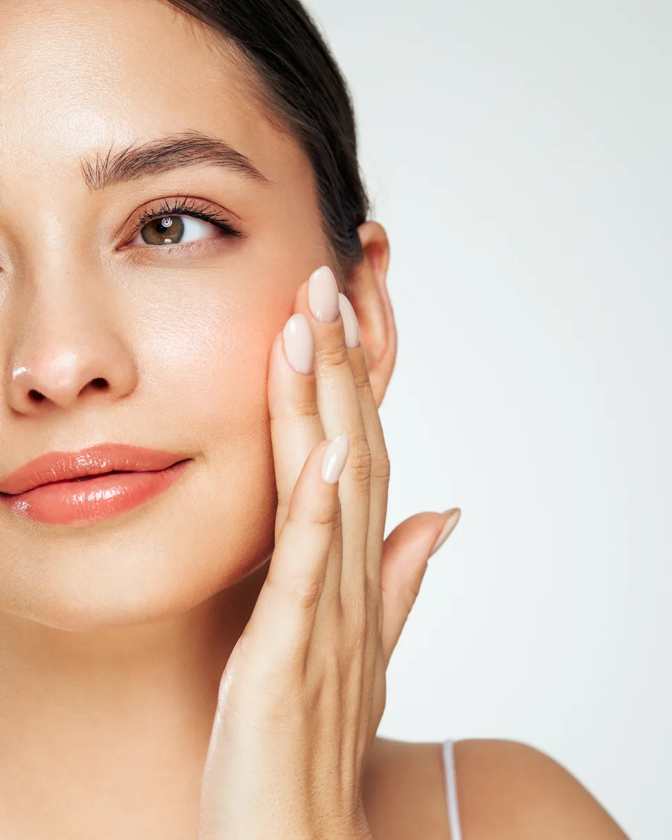 Woman with hydrated, glowing skin touching her cheek
